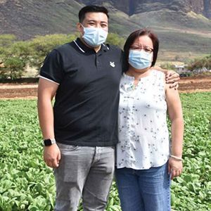 Mother and son hugging outside in field while wearing masks.