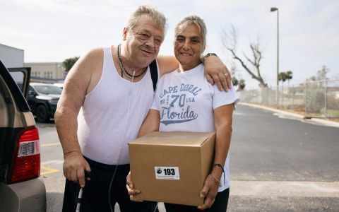 An elderly couple holding a food box.