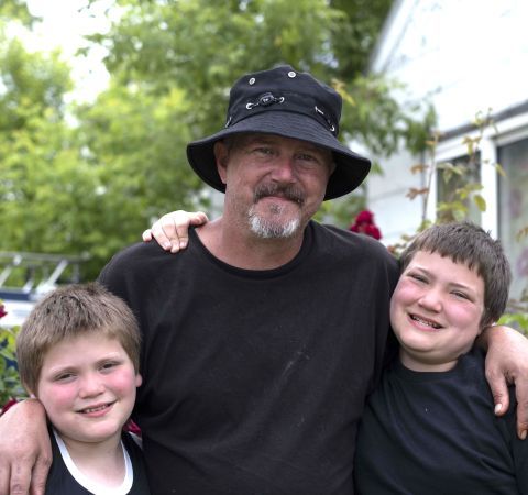 A man and his sons standing in front of a house.