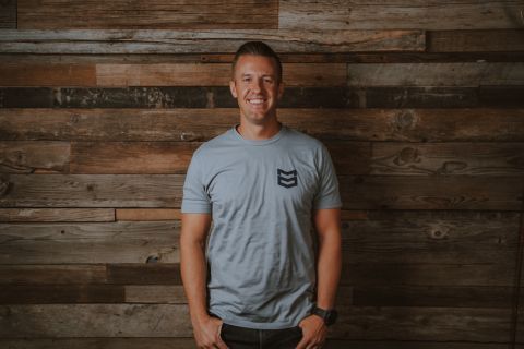 Trevor Farnes standing in front of a wood plank feature wall.