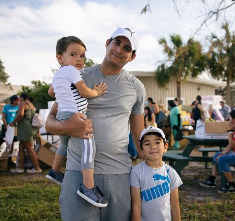 A father and his two young children at a food distribution site.