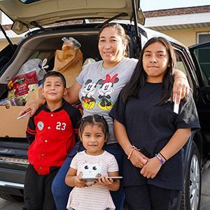 A family standing in front of the trunk of their car.