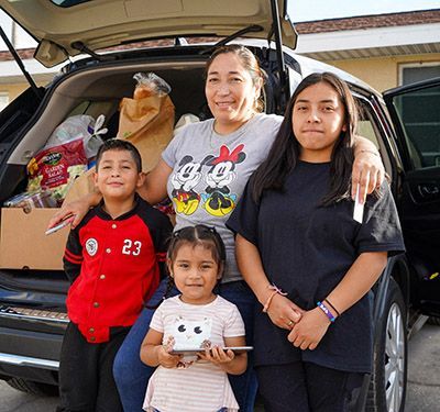 A family standing in front of a car trunk.