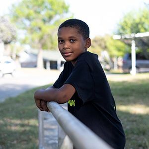 A child leaning on a fence.