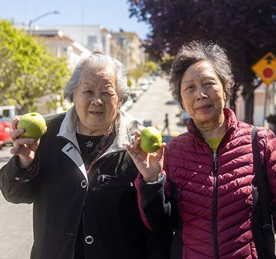 Two elderly women holding apples.