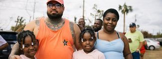 A family standing outside while smiling at the camera.