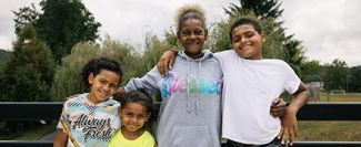 A family smiling while standing outside.