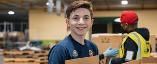 Volunteer holding a box in a warehouse.